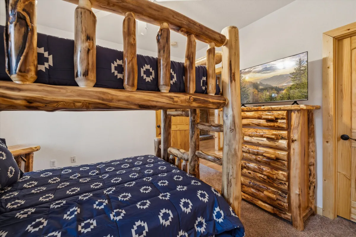 A welcoming bunk bed setup with a wooden dresser and television, creating an atmosphere geared towards fun and bonding. The playful arrangement hints at lively evenings and shared memories, especially for families or groups.