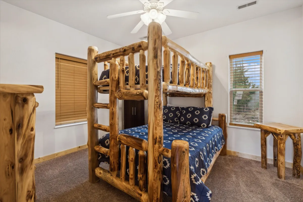 A welcoming bedroom with a bunk bed, wooden side table, and large windows. The space is lively yet cozy, flooded with natural light and playful touches—ideal for families or groups of friends.