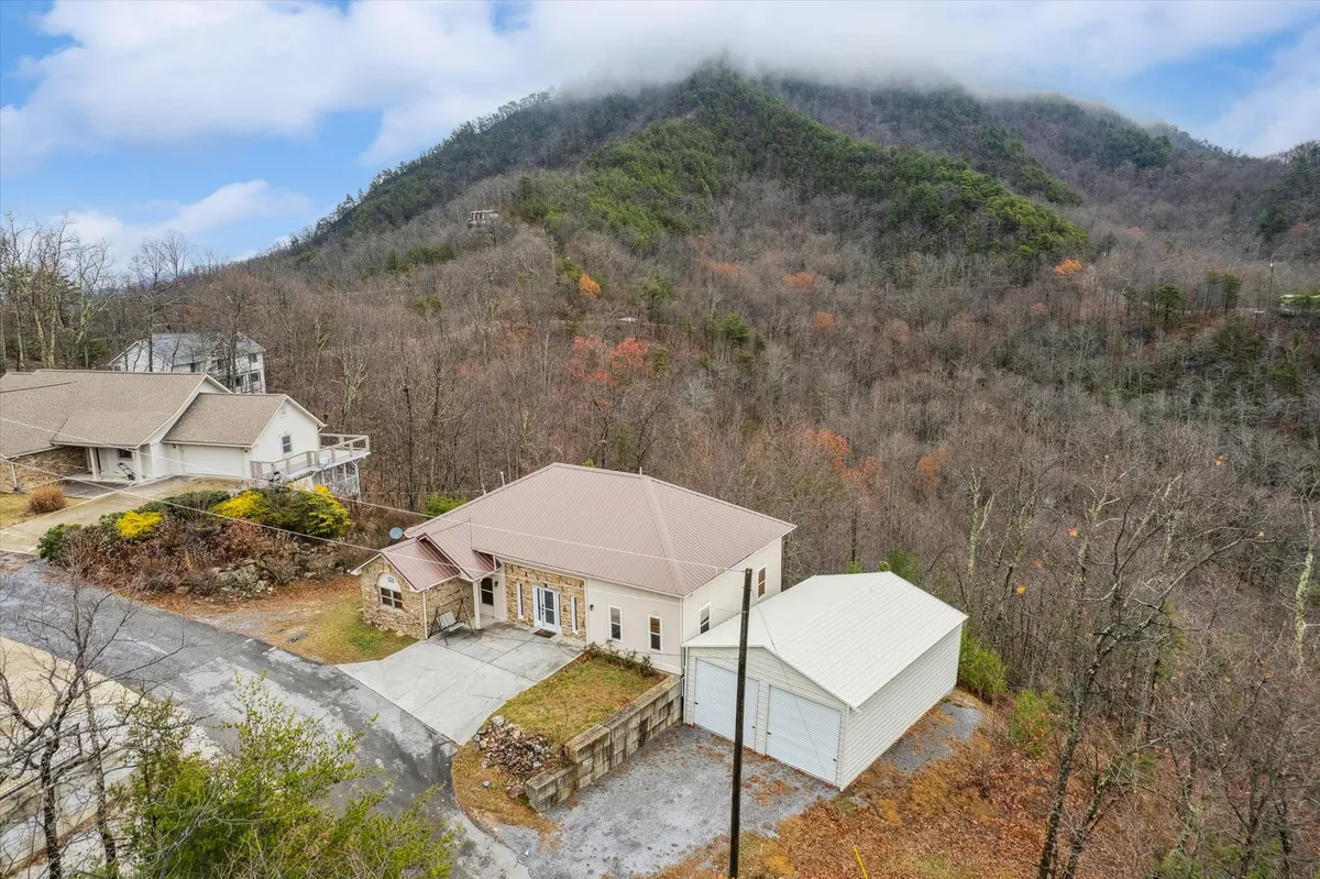 This image captures the exterior of the house nestled among the Smoky Mountains, with expansive views of the mountains, a driveway leading up to the home, and a garage. The lush natural setting invites visitors to imagine hiking, relaxing on the porch, and enjoying nature right outside the door.
