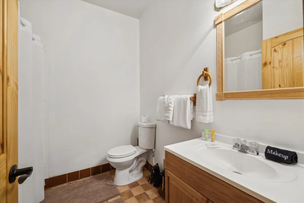 A practical and inviting bathroom with a vanity sink, mirror, toilet, and neatly arranged towels. The space is functional yet warm, perfect for morning routines or unwinding after a long day.